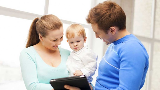 new parents and baby looking at tablet computer